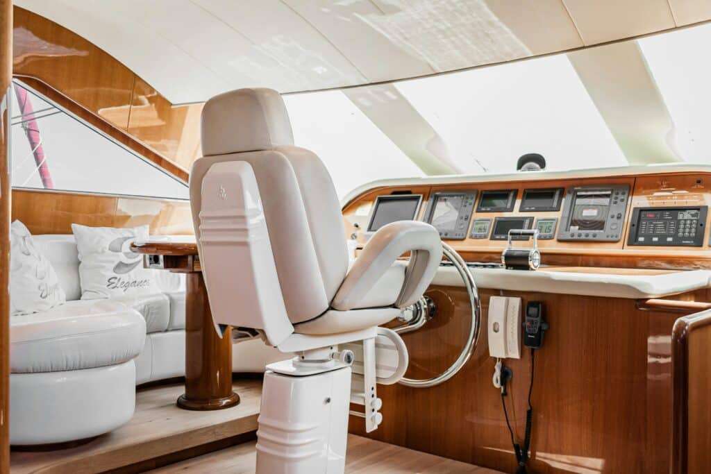 Luxurious yacht cockpit with beige captain's chair, wood-paneled dashboard, and navigation screens.