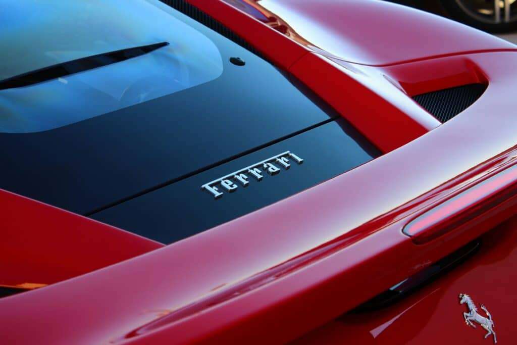 Close-up of a red Ferrari hood with the iconic prancing horse emblem and glossy paint finishing.