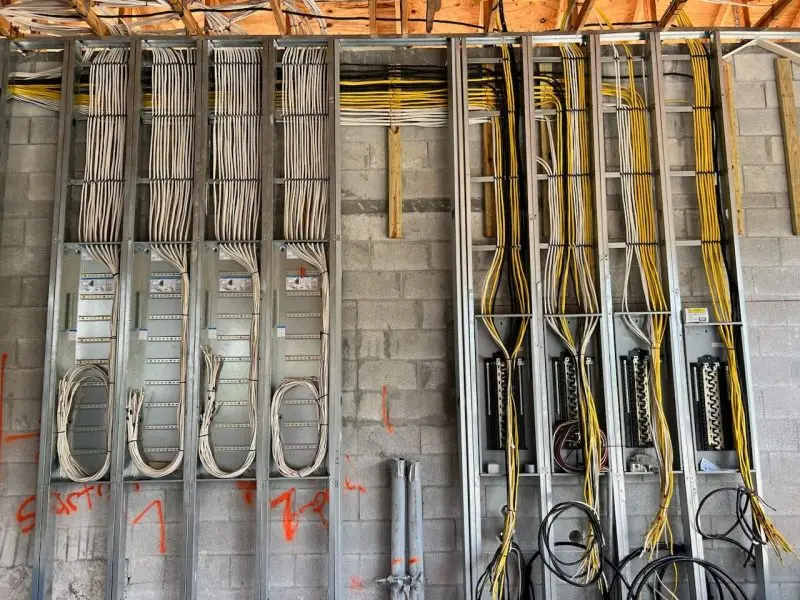 Professional electrical rough in installation by Ronin Development featuring organized wiring, multiple electrical panels, and precision craftsmanship behind the walls of a luxury custom home.