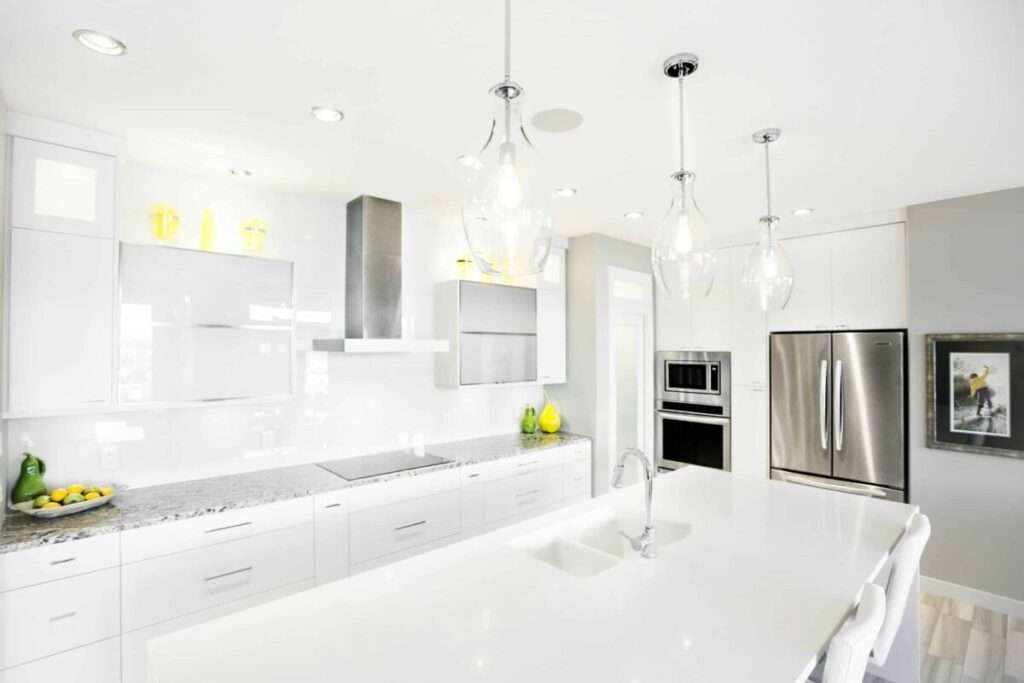 Modern luxury kitchen featuring white quartz countertops, waterfall island, custom cabinetry, stainless steel appliances, pendant lighting, and premium finishes in a South Florida custom home.
