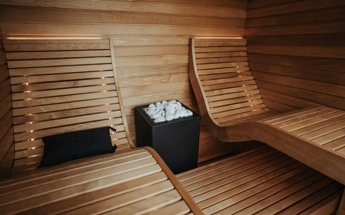 Luxury home sauna with wood loungers, integrated lighting and sauna heater