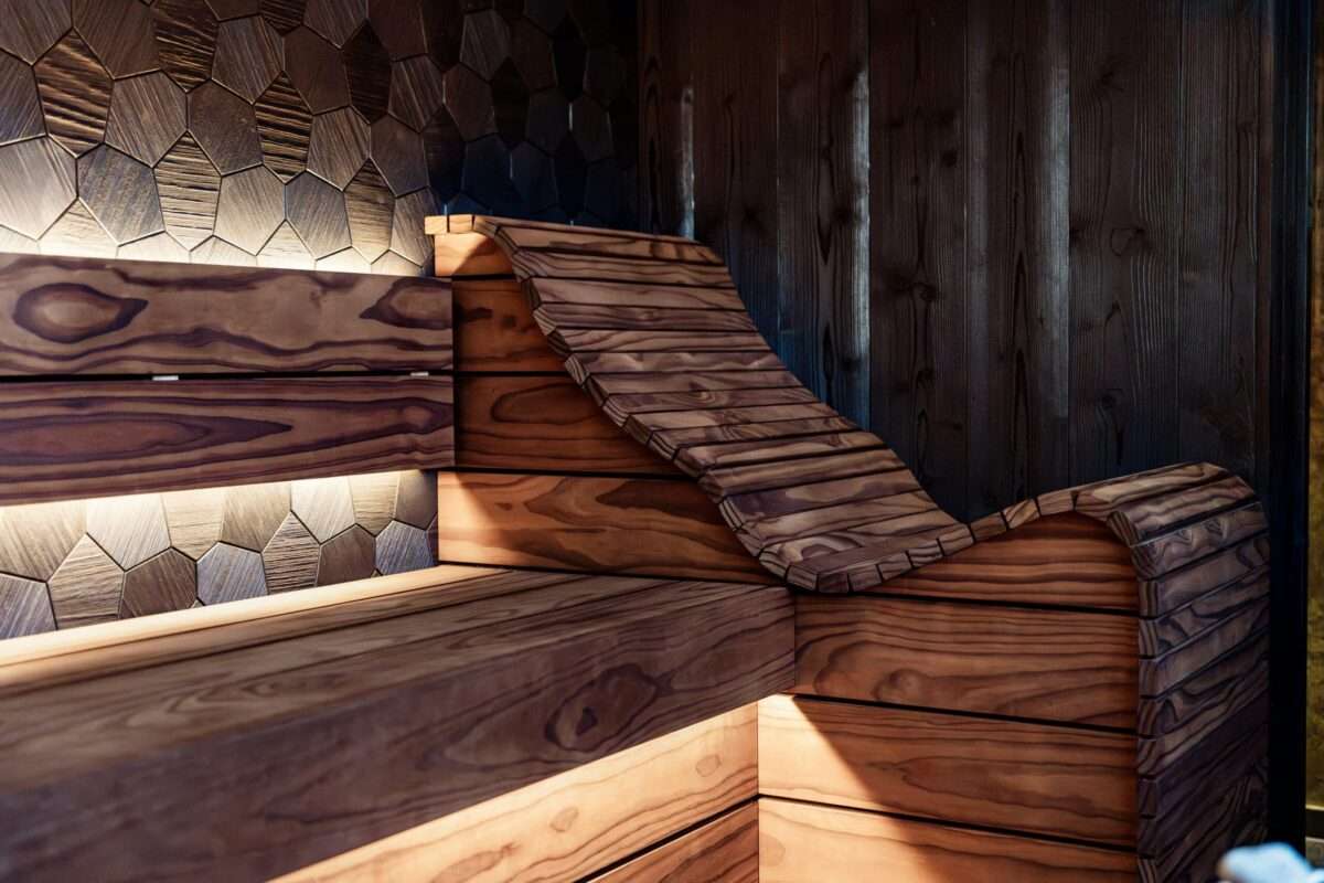 Custom luxury home sauna with sculpted wood lounger and architectural lighting