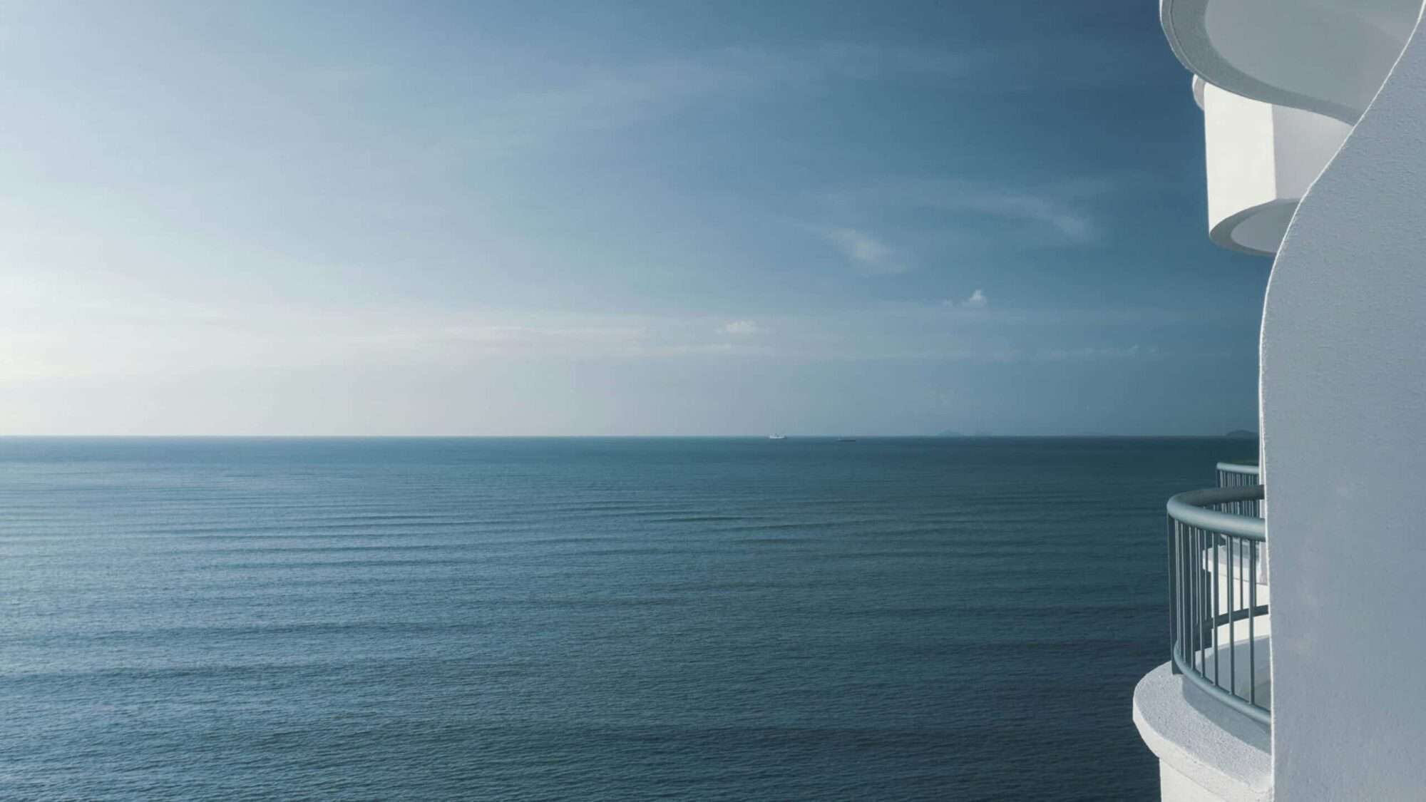 Oceanfront luxury home balcony overlooking expansive blue water and coastal horizon