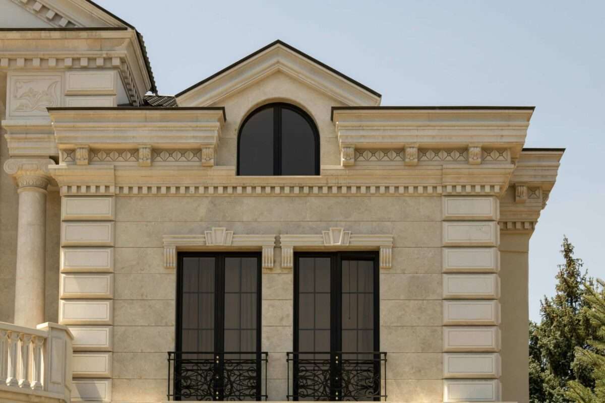 Luxury custom home exterior featuring detailed stone architecture, arched windows, columns, and decorative craftsmanship