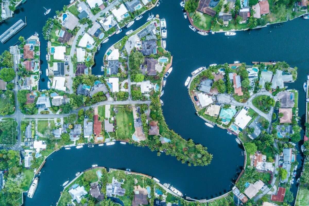 Aerial view of waterfront homes along winding canals with private docks, boats and swimming pools